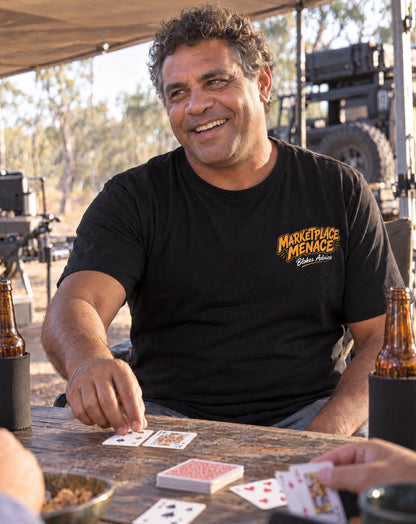 Smiling bloke at a bush camp wearing the black Marketplace Menace Tee with orange left chest logo
