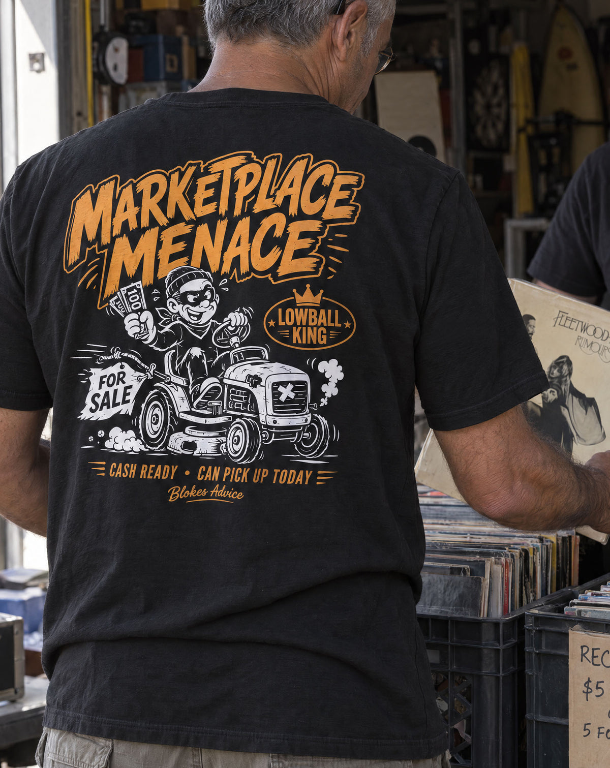 Marketplace Menace Tee back print in orange, worn by a bloke flipping through records at a market stall